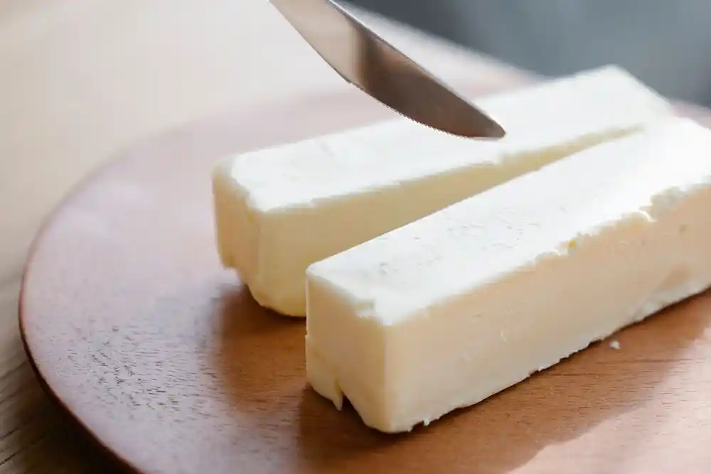 Ahşap tabakta iki parça tereyağı ve üzerlerinde duran bıçak
